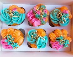 six cupcakes in a box decorated with colorful icing