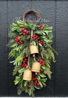 a christmas wreath with bells hanging on the front door, decorated with holly and red berries