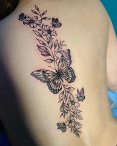 a woman's back with butterflies and flowers on it