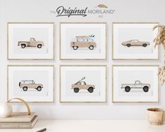 four framed pictures with cars on them in front of a white wall and a potted plant