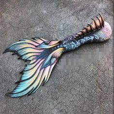 a fish tail laying on the ground with it's feathers painted multicolored