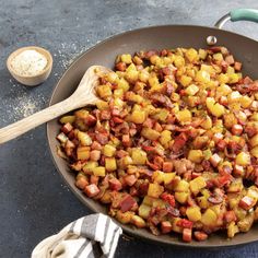 a pan filled with cooked food on top of a table next to a wooden spoon