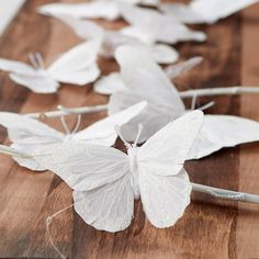 some white butterflies are laying on a wooden table