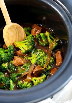 crockpot beef and broccoli in a slow cooker with a wooden spoon