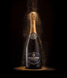 a bottle of champagne is being sprinkled with gold dust on a black background