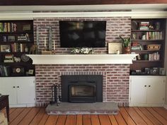 a living room with a fire place and bookshelves on the wall above it