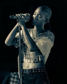 a black and white photo of a woman singing into a microphone