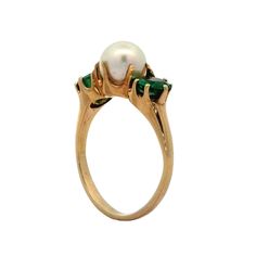 This Victorian three-stone ring combines antique design with sophisticated style. At its center is a 6.8 mm pearl, exuding a soft, lustrous glow. Flanking the pearl are two round cut emeralds, each weighing .46 carats and measuring 5.0 mm, prong-set to catch the light beautifully. Crafted in 14 karat yellow gold and polished to a high shine, this ring enhances the natural beauty of the gems and pearl. Its elegant design makes it a wonderful addition to any collection, perfect for those who appreciate the artistry of antique jewelry. Platinum Rose Gold, Sapphire Solitaire, Antique Design, The Pearl, Shop Engagement Rings, Three Stone Rings, Emerald Ring, Antique Victorian, Three Stone