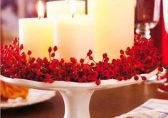 three candles on a cake stand with red flowers