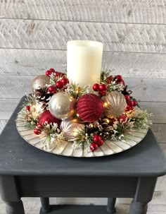 a candle sits on top of a plate with christmas decorations and baubles around it