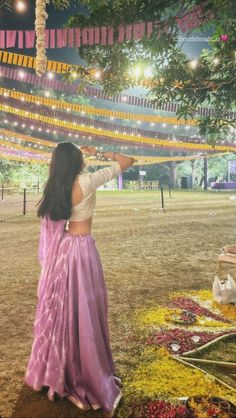 a woman standing under a tree with lights strung from the branches above her and in front of it