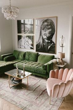 a living room with green couches and pictures on the wall above them, as well as a chandelier