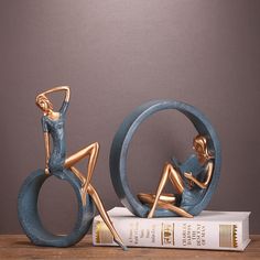 a gold and blue statue sitting on top of a book next to a stack of books