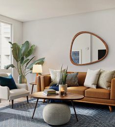 a living room filled with furniture and a large round mirror on the wall above it