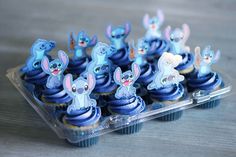 some cupcakes with blue frosting are in a plastic container on a table