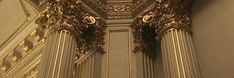 an ornate gold clock on the side of a wall in a room with white walls