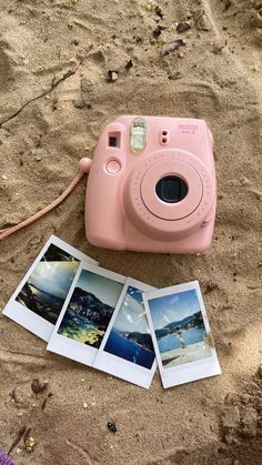 a pink camera sitting on top of a sandy beach next to three polaroid pictures