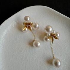 two white pearls are attached to gold - plated ear pins on a white plate