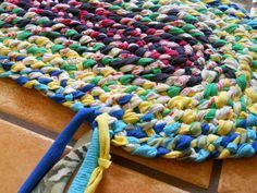 a multicolored round rug on the floor with a blue handle next to it