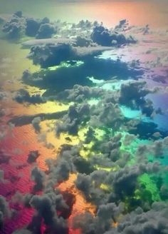 an aerial view of clouds and the sky with rainbow colors in it's center