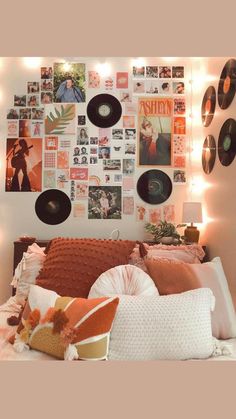 a bed topped with lots of pillows next to a wall covered in pictures and records