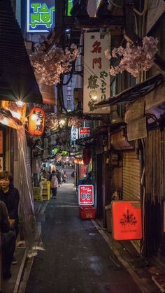 an alley way with people walking down it at night in the middle of the city