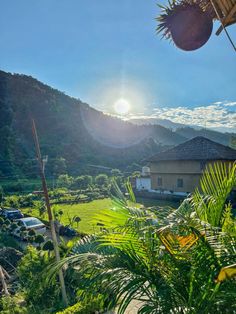 the sun shines brightly over a lush green valley with houses and mountains in the background