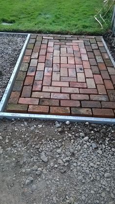 a brick patio being built in the middle of a yard with gravel and grass around it