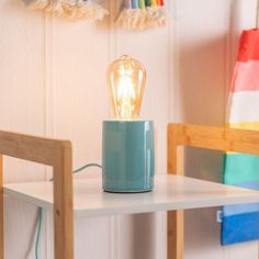 a table with a lamp on top of it next to a chair and rainbow wallpaper