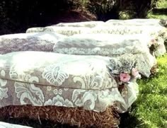 there are many couches that have been covered with fabric and flowers on them in the grass