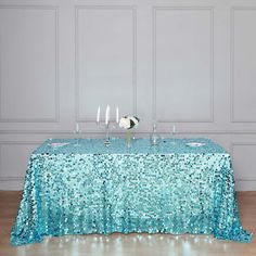 the table is covered with blue sequins and has candles on it, along with white flowers