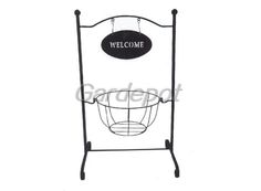 a welcome sign hanging from the side of a metal stand with a basket on it