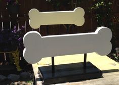 a wooden sign with a dog bone on it's back end in front of a fence