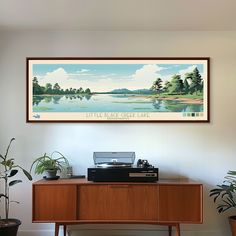 a painting hanging on the wall above a desk with a typewriter and potted plants