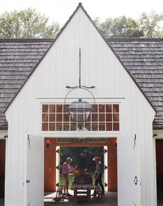 two people standing in the doorway of a white barn