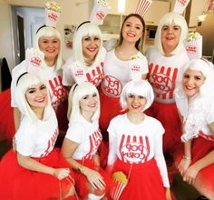 a group of women dressed in red and white outfits posing for a photo with popcorn on their heads