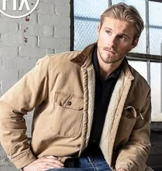 a man sitting on top of a chair in front of a window wearing a jacket