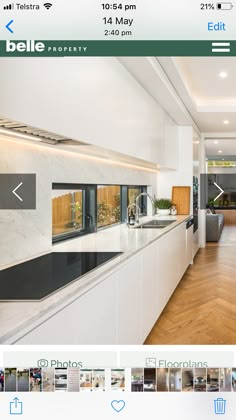 an iphone photo of a kitchen with white cabinets and wood flooring on the phone screen