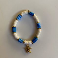 a white bracelet with blue and gold beads and a starfish charm hanging from it