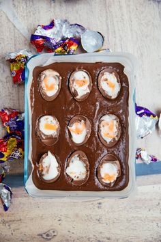 an ice cream tray filled with chocolate covered eggs and marshmallows on top of a wooden table