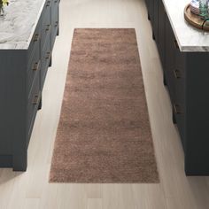 a large kitchen with gray cabinets and white counter tops, along with a brown rug on the floor