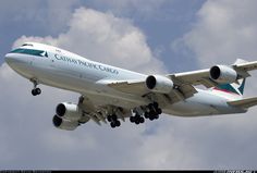 a large passenger jet flying through a cloudy blue sky with the words cathay pacific airlines on it's side