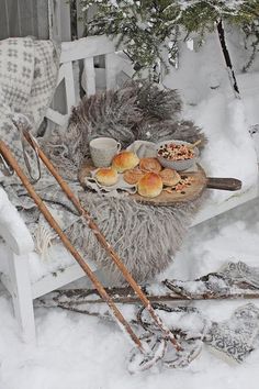 a picnic table with bread and pastries on it in the snow