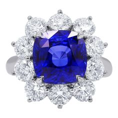 a blue and white ring with diamonds around it on a white background, the center stone is surrounded by three rows of round brilliant cut stones