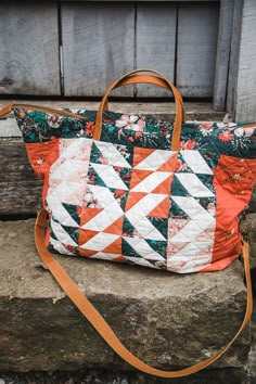 an orange and white quilted bag sitting on top of a stone wall next to a wooden door