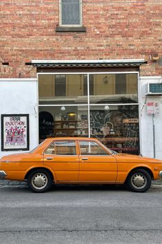 an orange car parked in front of a store