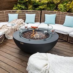 a fire pit sitting on top of a wooden deck next to pillows and blankets covered in blankets