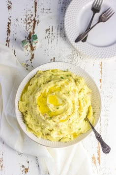 a white bowl filled with mashed potatoes on top of a table next to a fork