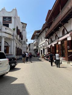 people are walking down the street in front of some white buildings with balconies