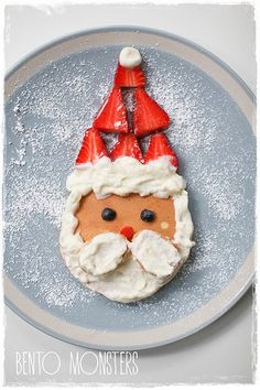 a plate with some food on it that looks like santa claus's face and has strawberries in his mouth